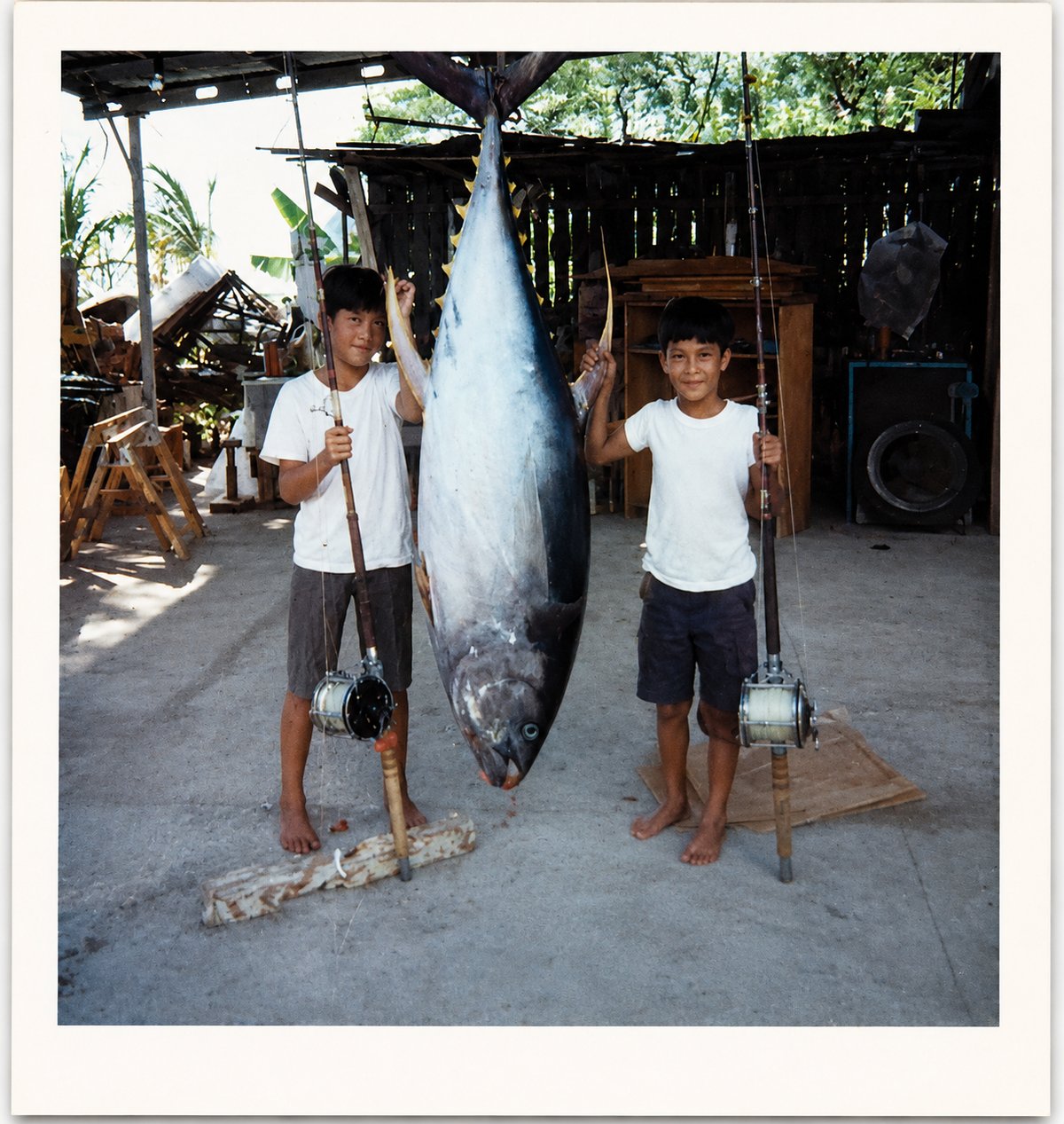 Kahili and his older brother as kids in Waianae, Oahu, standing next to a large ahi their father caught